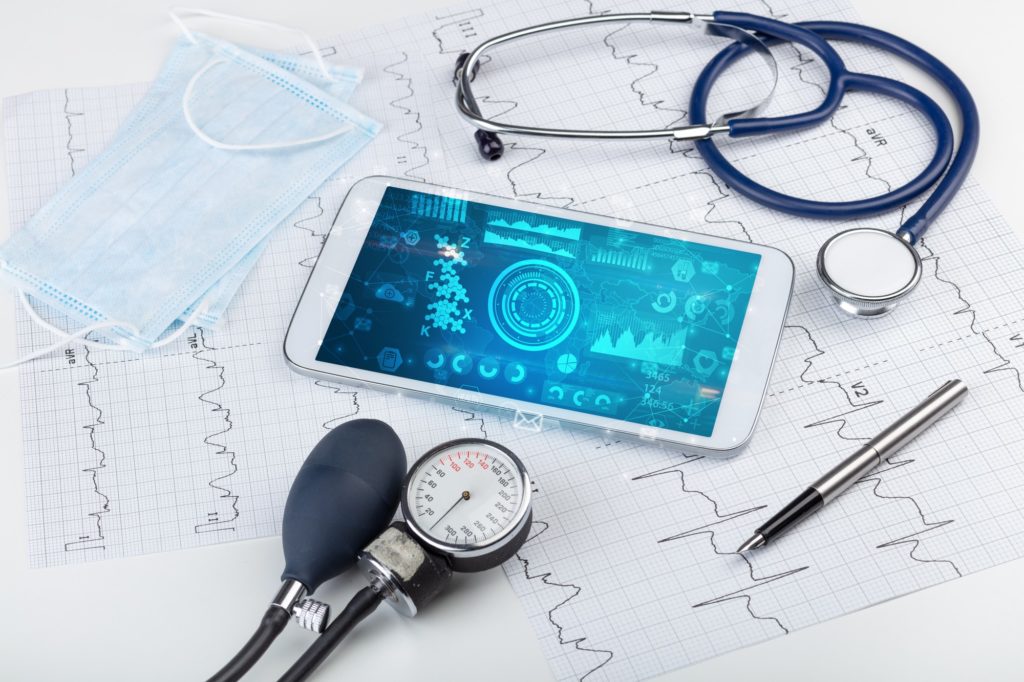 celular com diagrama de dados, estetoscópio e ferramenta de aferição de pressão representando saúde baseada em valor