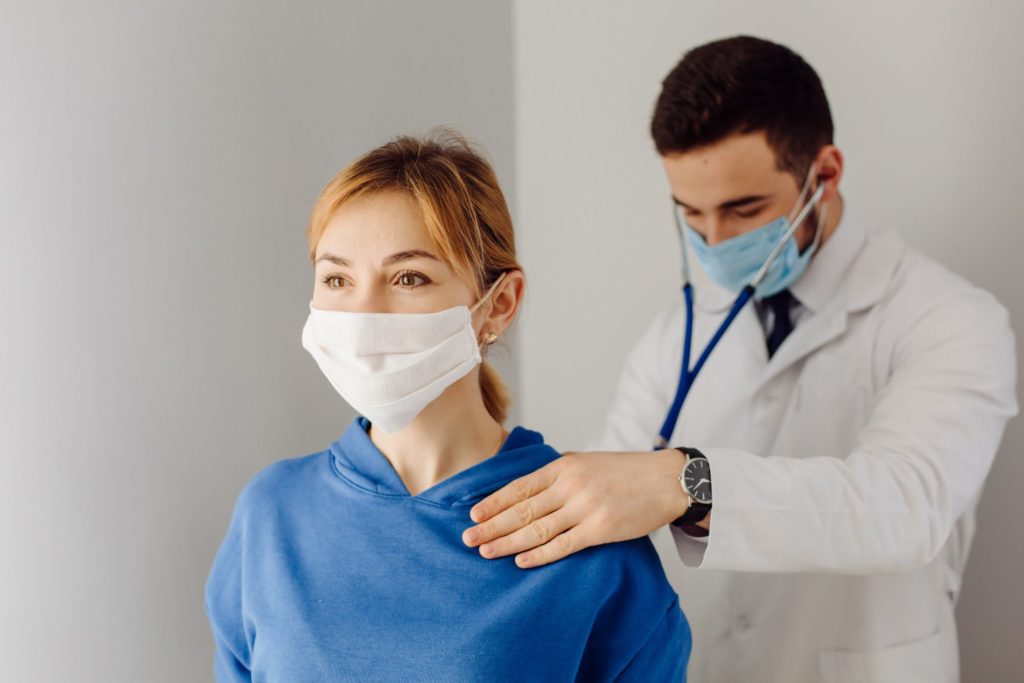 médico ouvindo o pulmão da paciente, colocando a medicina preventiva em prática